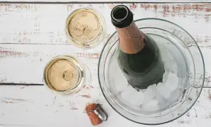Due bicchieri di Prosecco e una bottiglia in un secchiello di ghiaccio. La temperatura ideale per il Prosecco è tra 6-8 gradi.