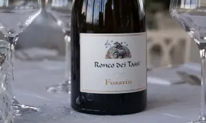 Bottiglia di vino Fosarin Ronco dei Tassi, tra calici pronti per degustare i vini del Collio.