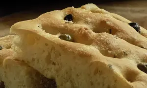 Focaccia soffice con olive e rosmarino, perfetta da gustare con un buon vino.