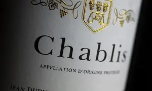 Etichetta di un vino bianco francese Chablis, con stemma dorato e grappoli d'uva.