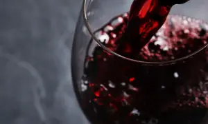 Versando vino rosso rubino in un calice, evocando i sapori autentici dei vini lucani.