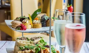 Delizioso abbinamento champagne con pasticcini, macarons, fragole e tartine su un elegante espositore a più livelli.
