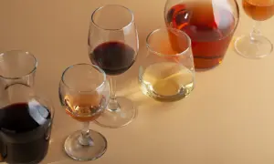 Bicchieri e caraffe con vino rosso, bianco e rosato. Un bicchiere di vino rosso, forse un Merlot, risalta tra gli altri.
