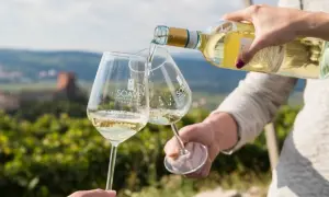 Versando soave wine in due calici con sfondo di vigneti e castello.