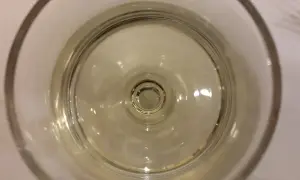 Un bicchiere di vino resinato, con riflessi dorati che danzano sul fondo.
