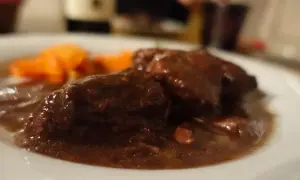 Brasato al Barolo ricetta originale piemontese: tenera carne cotta lentamente nel vino rosso, servita con carote.