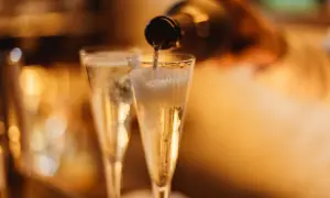 Versando vino spumante di qualità in due flute, le bollicine creano una schiuma invitante.