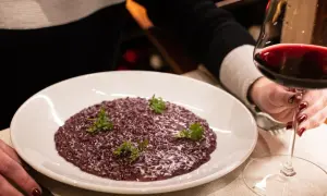Risotto viola, perfetto abbinamento amarone. Un bicchiere di vino rosso intenso accompagna questo piatto raffinato.