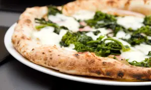Pizza con verdure e mozzarella su un piatto bianco, un'ottima scelta per una serata con pizza e champagne.