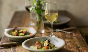 Deliziosi piatti con pesce e verdure, perfetti per i pinot grigio abbinamenti. Un bicchiere di vino bianco attende accanto a un bouquet di fiori.