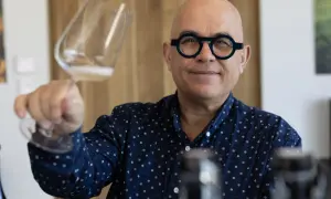 Uomo con occhiali rotondi tiene un bicchiere di champagne Francia, sorridendo.