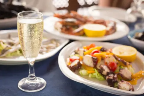 Calice di champagne con stuzzichini per aperitivo: polpo, gamberi e alici.