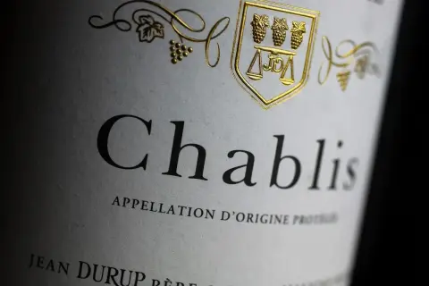 Etichetta di un vino bianco francese Chablis, con stemma dorato e grappoli d'uva.