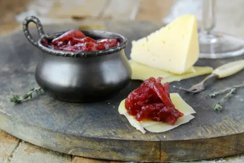 Un delizioso abbinamento formaggi marmellate e vino: formaggio stagionato con cipolle rosse caramellate, pronto per essere gustato.