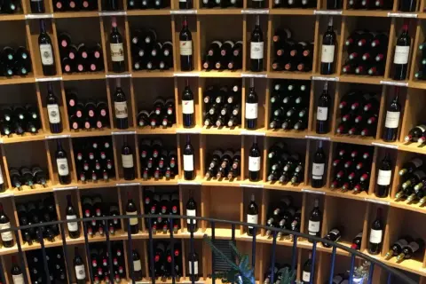 Scaffali pieni di bottiglie di vino, tra cui un ottimo vino di Bordeaux, in una cantina.
