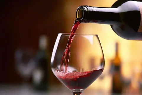 Versando vino rosso in un calice, un assaggio dei migliori Barolo.