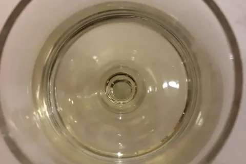 Un bicchiere di vino resinato, con riflessi dorati che danzano sul fondo.