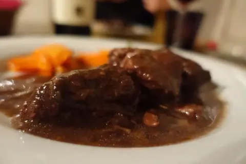Brasato al Barolo ricetta originale piemontese: tenera carne cotta lentamente nel vino rosso, servita con carote.