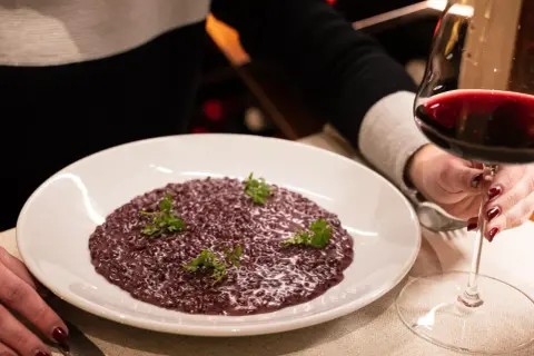 Risotto viola, perfetto abbinamento amarone. Un bicchiere di vino rosso intenso accompagna questo piatto raffinato.