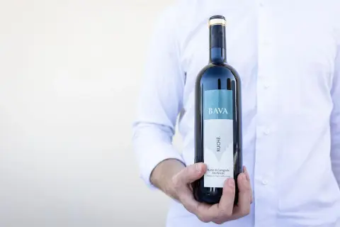 Uomo in camicia bianca tiene una bottiglia di vino Ruche di Castagnole Monferrato BAVA.