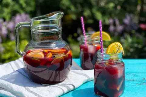 Rinfrescante sangria all'italiana in caraffa e bicchieri, con fette d'arancia e lime, pronta per un picnic estivo.