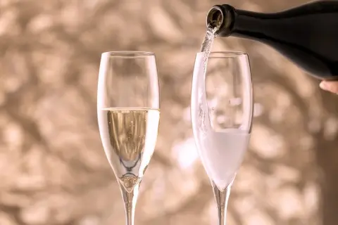 Versando vino in un bicchiere, creando bollicine che ricordano il vino frizzante.
