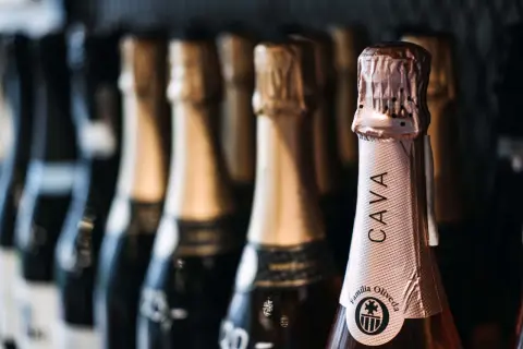 Bottiglie di cava spagnolo in fila. La bottiglia in primo piano mostra l'etichetta "CAVA Familia Oliveda".
