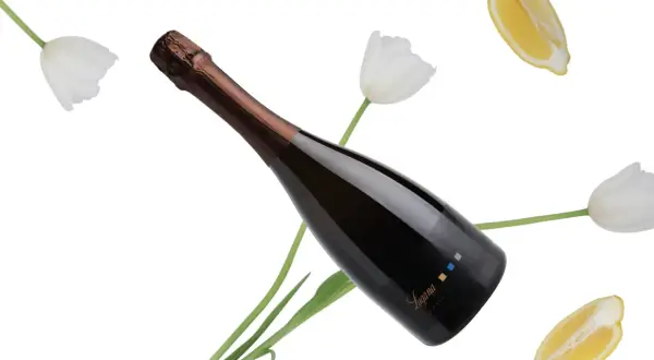 Bottiglia di spumante Trebbiano di Lugana tra tulipani bianchi e fette di limone, con un'etichetta che riporta il nome "Lugana".