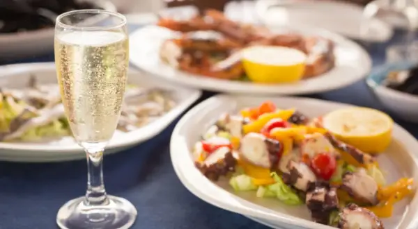 Calice di champagne con stuzzichini per aperitivo: polpo, gamberi e alici.