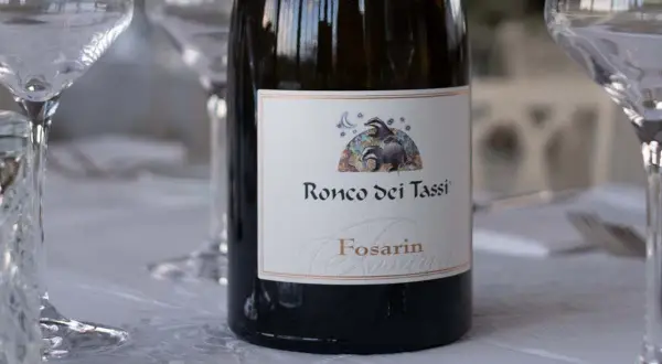Bottiglia di vino Fosarin Ronco dei Tassi, tra calici pronti per degustare i vini del Collio.