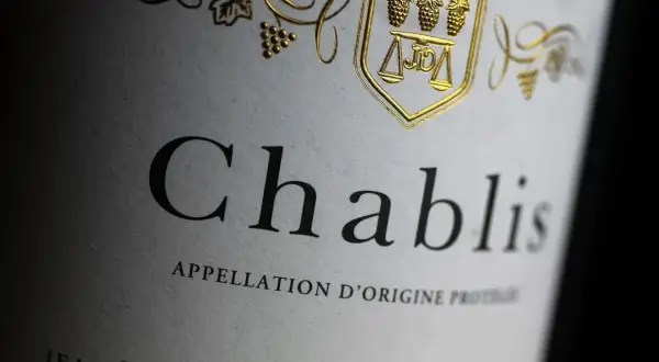 Etichetta di un vino bianco francese Chablis, con stemma dorato e grappoli d'uva.