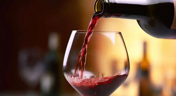Versando vino rosso in un calice, un assaggio dei migliori Barolo.