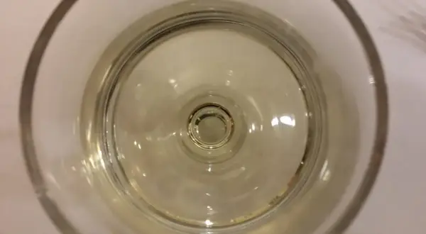 Un bicchiere di vino resinato, con riflessi dorati che danzano sul fondo.