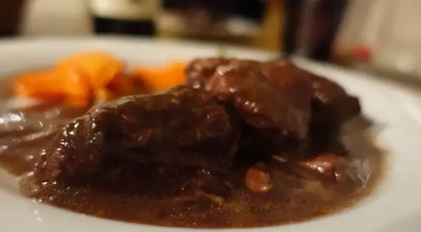 Brasato al Barolo ricetta originale piemontese: tenera carne cotta lentamente nel vino rosso, servita con carote.
