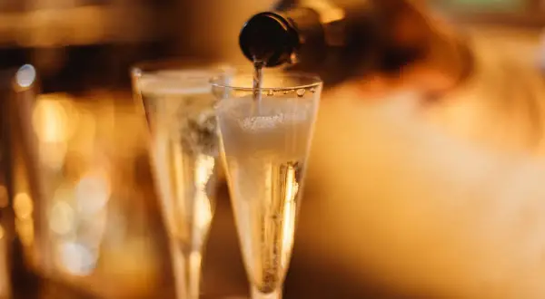 Versando vino spumante di qualità in due flute, le bollicine creano una schiuma invitante.