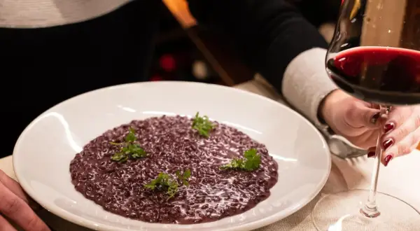 Risotto viola, perfetto abbinamento amarone. Un bicchiere di vino rosso intenso accompagna questo piatto raffinato.