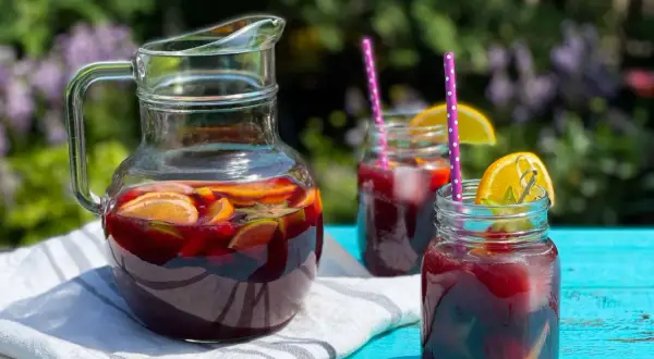Rinfrescante sangria all'italiana in caraffa e bicchieri, con fette d'arancia e lime, pronta per un picnic estivo.
