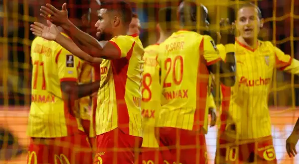Giocatori di calcio con maglie gialle e rosse, come il **vino** di **Saint-Joseph**, esultano dietro una rete.