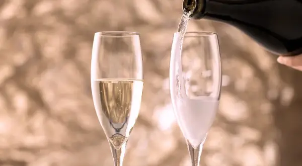 Versando vino in un bicchiere, creando bollicine che ricordano il vino frizzante.
