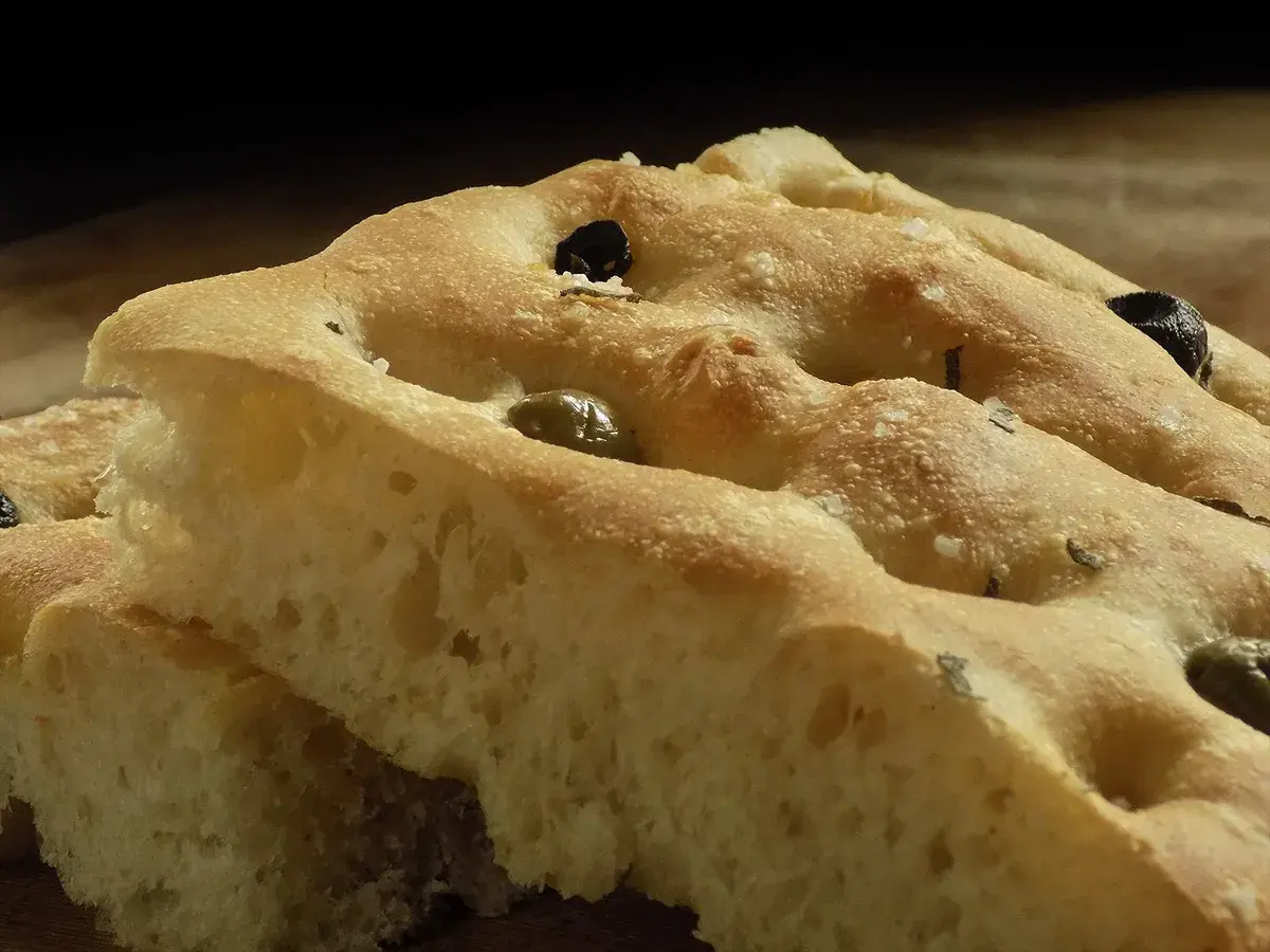 Focaccia soffice con olive e rosmarino, perfetta da gustare con un buon vino.