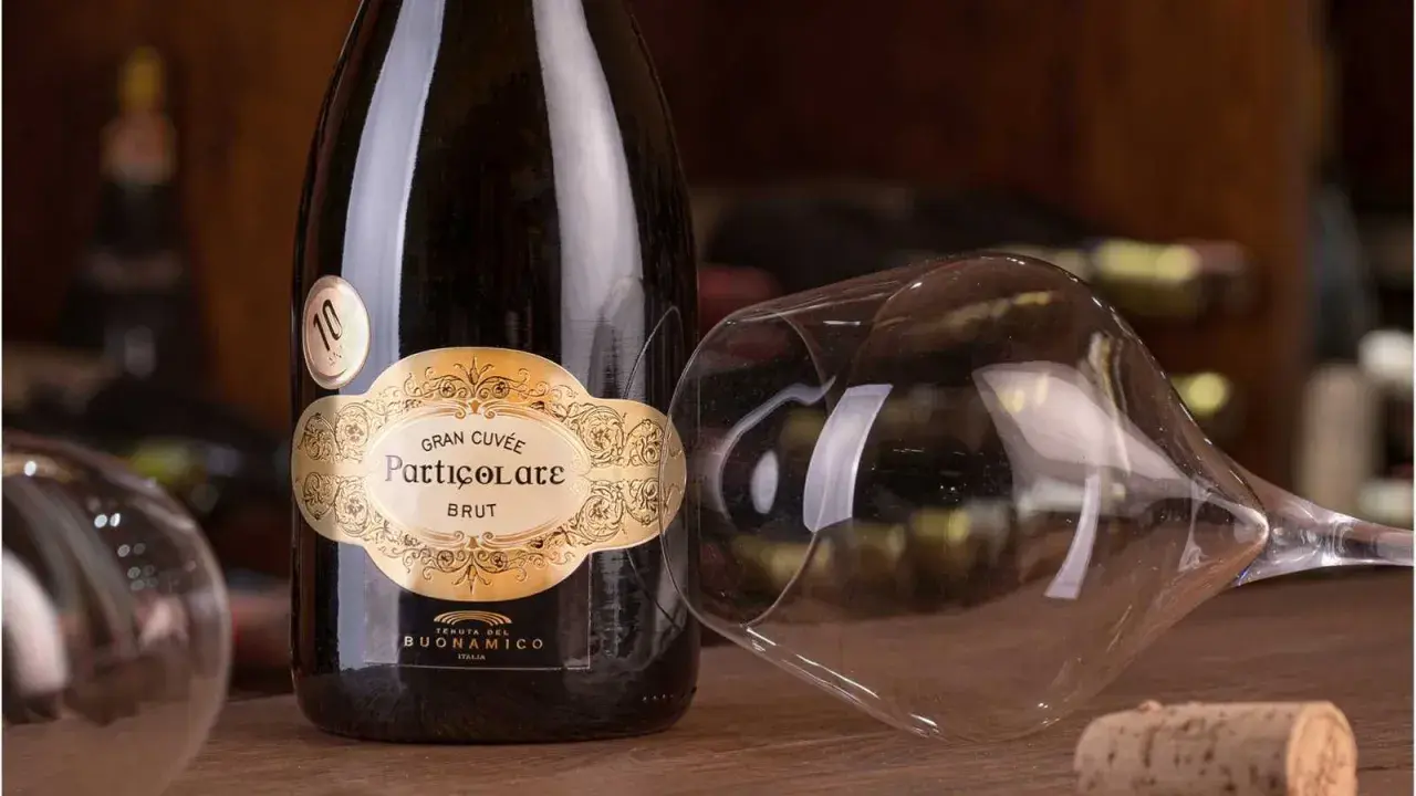 Bottiglia di spumante Gran Cuvée Particolare Brut, con calice rovesciato e tappo di sughero. Il "brut" indica la secchezza del vino.