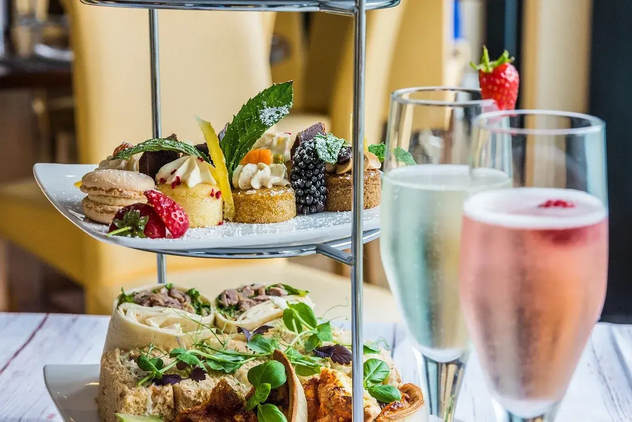 Delizioso abbinamento champagne con pasticcini, macarons, fragole e tartine su un elegante espositore a più livelli.