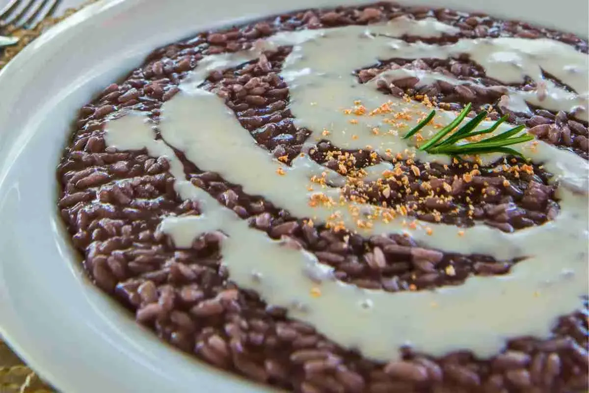 Un cremoso risotto all'amarone, con un filo di salsa bianca e un rametto di rosmarino.