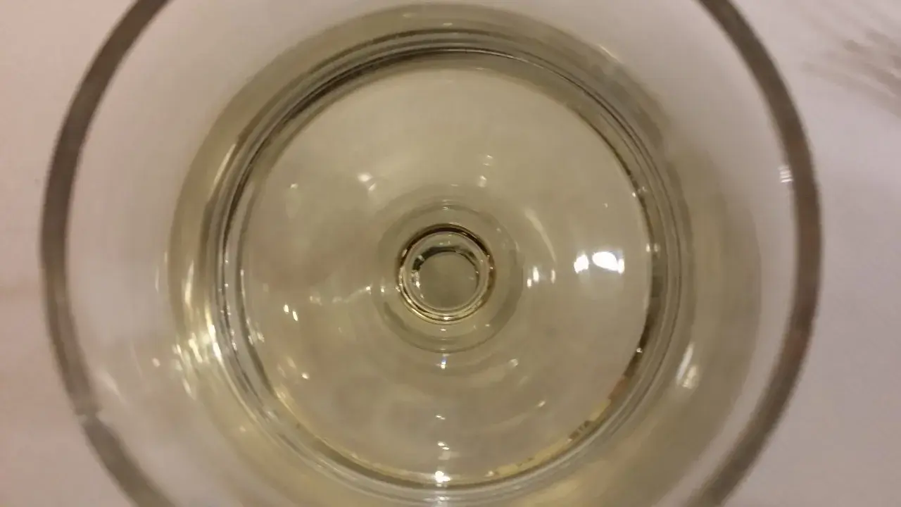 Un bicchiere di vino resinato, con riflessi dorati che danzano sul fondo.