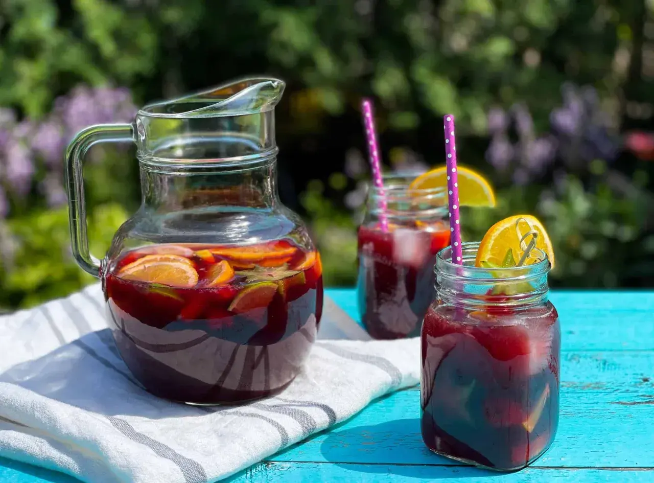 Rinfrescante sangria all'italiana in caraffa e bicchieri, con fette d'arancia e lime, pronta per un picnic estivo.