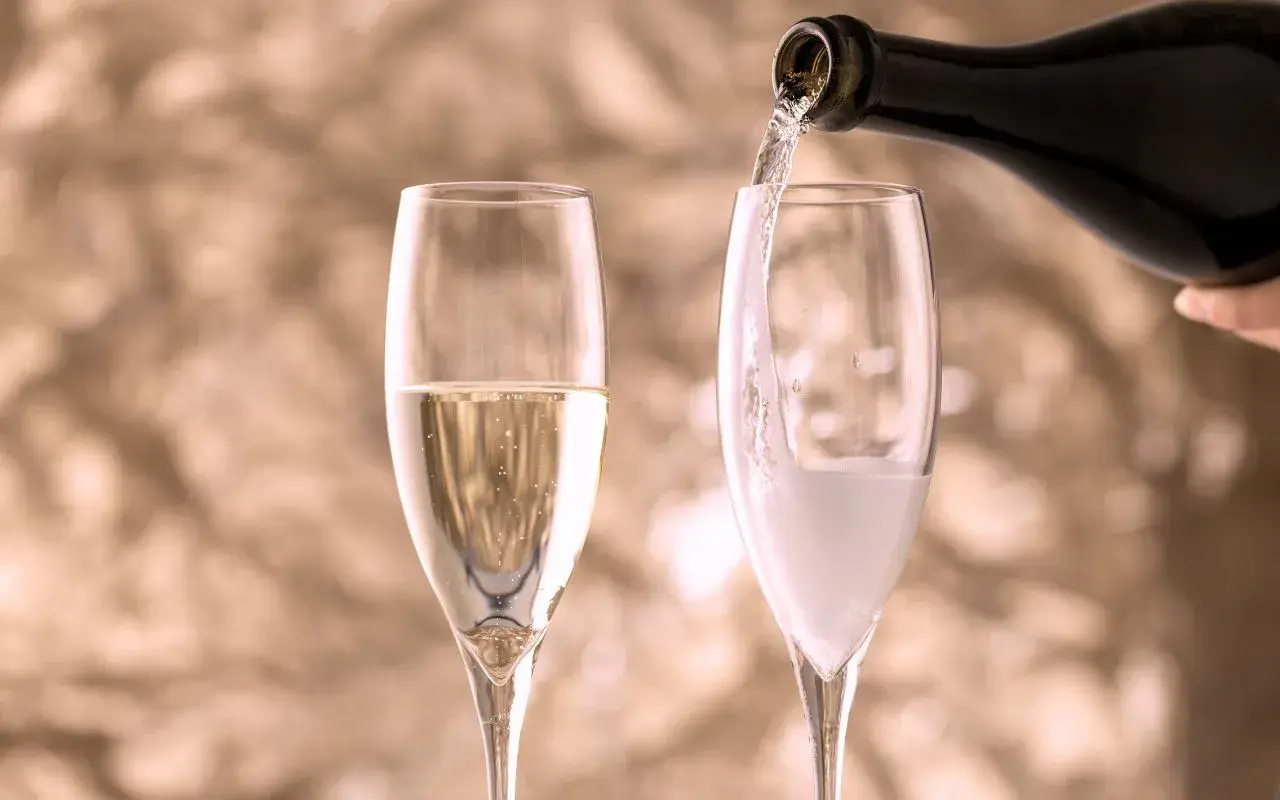 Versando vino in un bicchiere, creando bollicine che ricordano il vino frizzante.