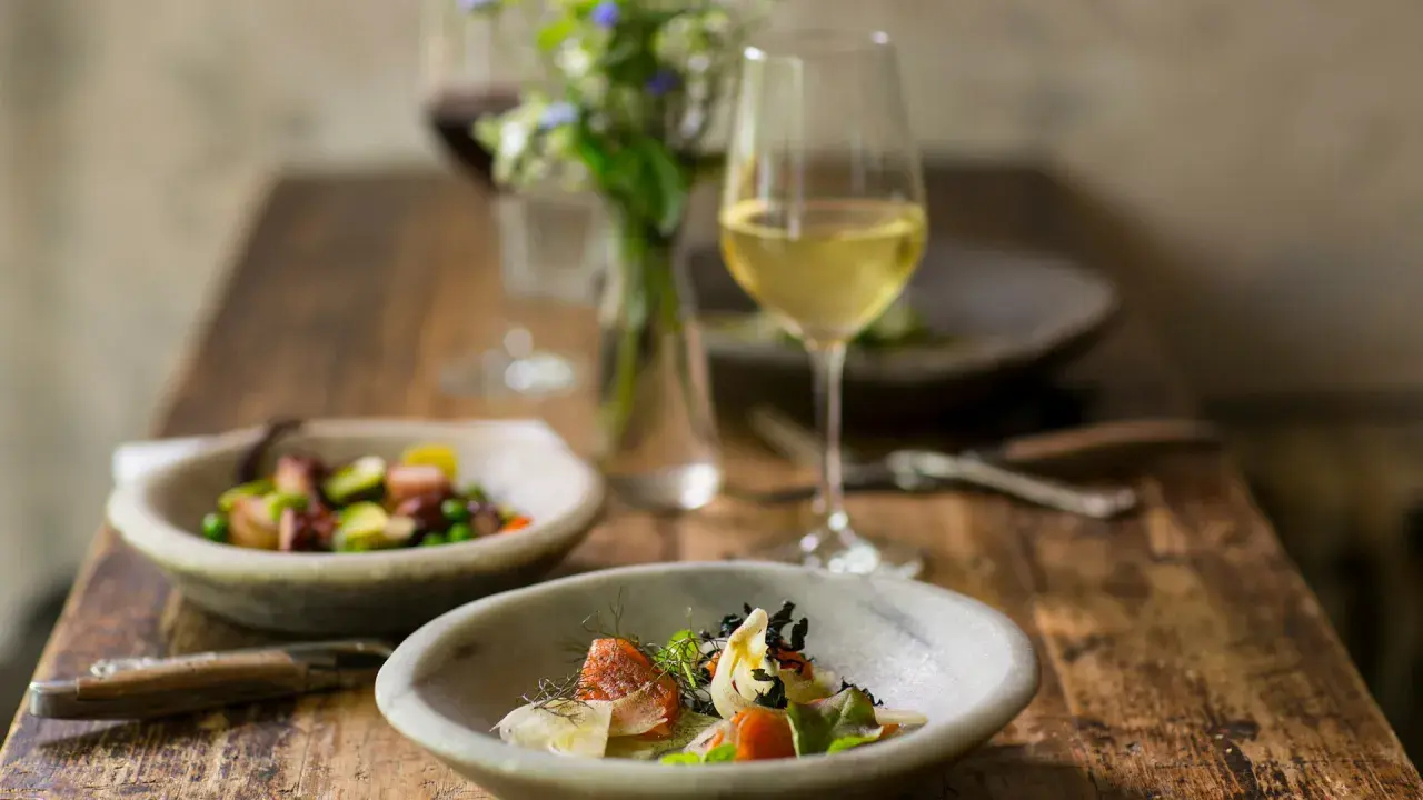 Deliziosi piatti con pesce e verdure, perfetti per i pinot grigio abbinamenti. Un bicchiere di vino bianco attende accanto a un bouquet di fiori.
