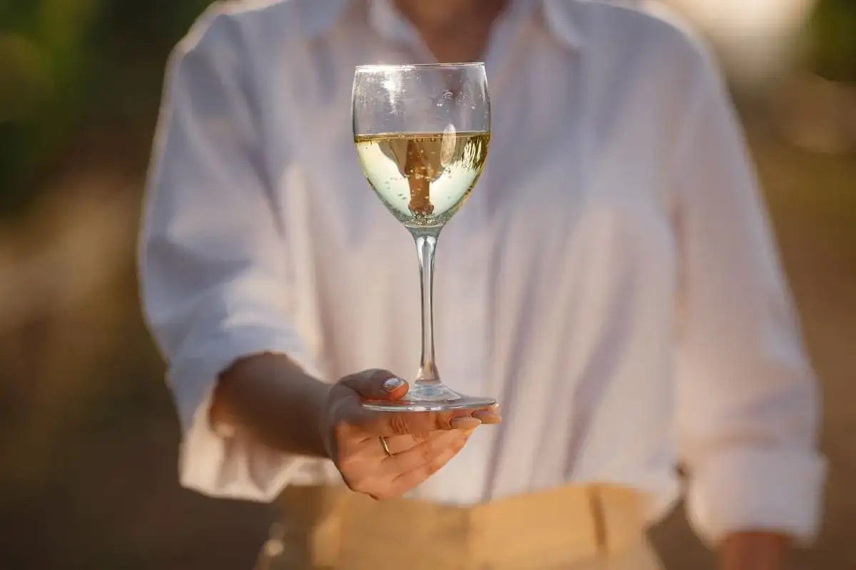 Calice di vino bianco altoatesino, riflessi dorati e bollicine danzanti. Un sorso di sole.