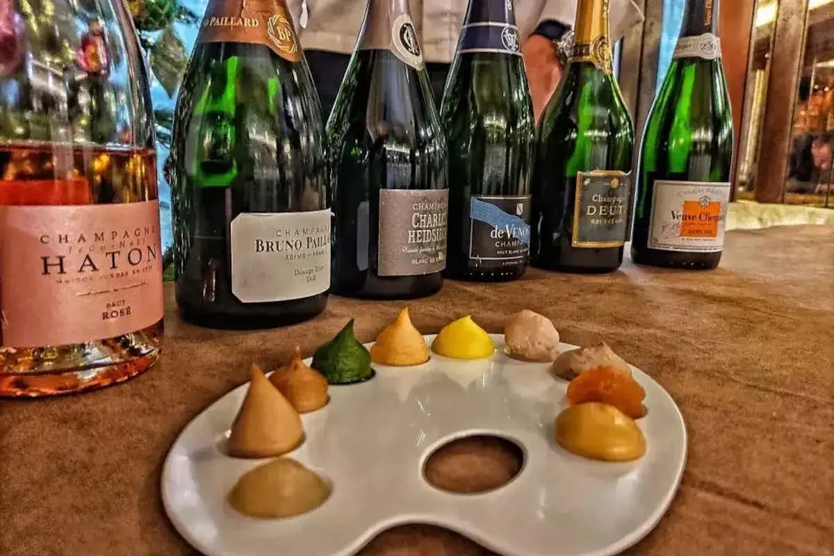 Un abbinamento champagne: diverse bottiglie di spumante e una tavolozza con assaggi colorati, pronti per essere gustati.