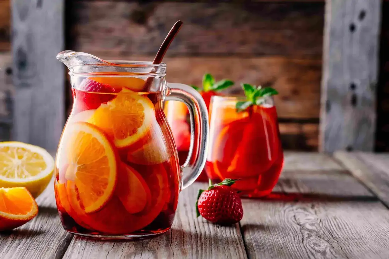 Caraffa e bicchieri pieni di sangria con arance, fragole e limone. Perfetta per fare la sangria in compagnia.